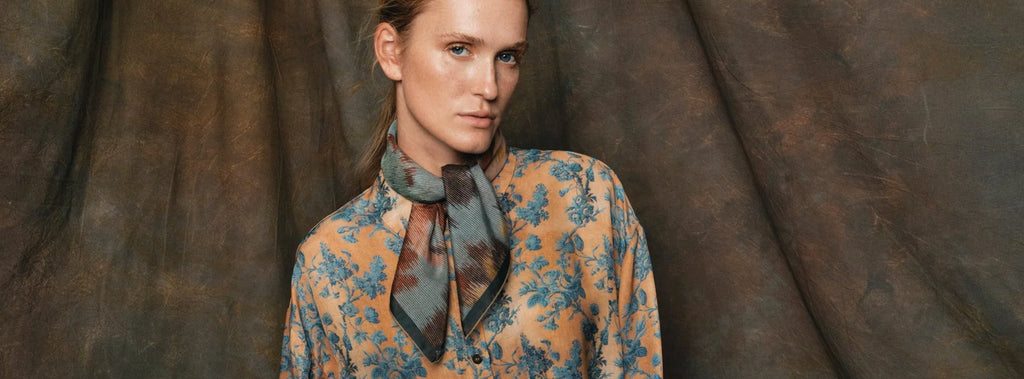 Get ready for Autumn with woman wearing floral blouse and scarf against brown backdrop