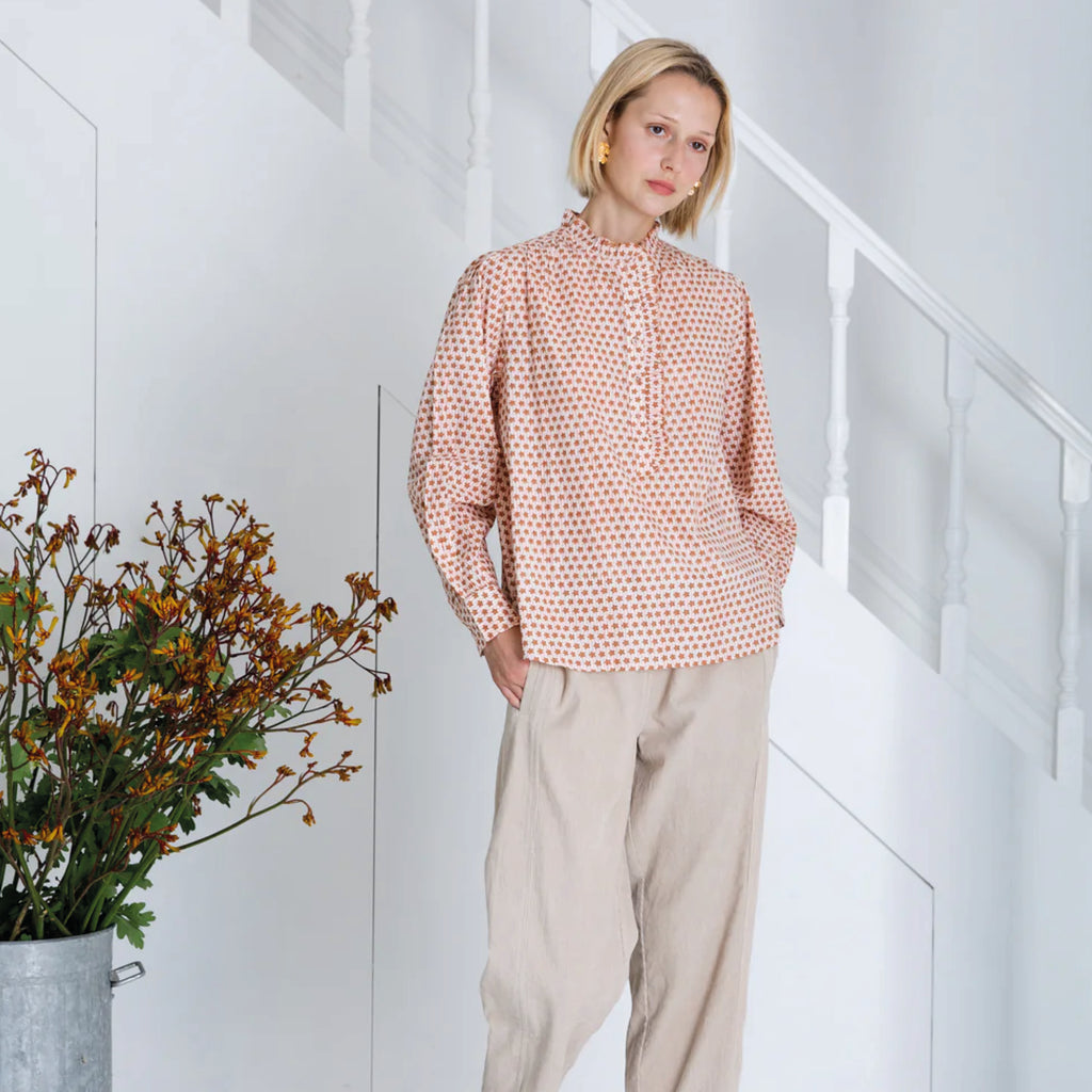 Red and white patterned blouse in cotton cambric woodblock print, with frill around the neck and front half placket.
Bonté Cinnamon Blush Anais Shirt - Jo And Co Bonté Cinnamon Blush Anais Shirt - Bonté