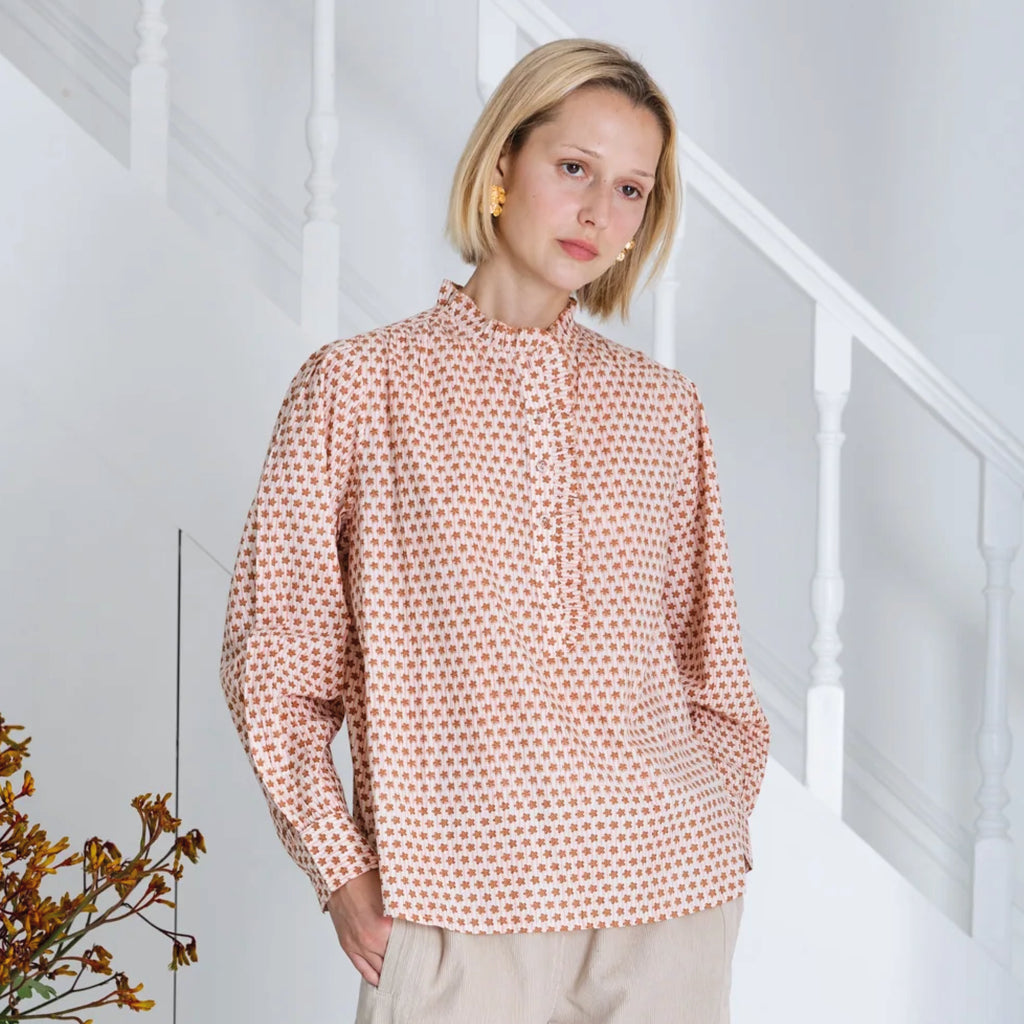 Red and white patterned blouse in cotton cambric woodblock print, with frill around the neck and front half placket.
Bonté Cinnamon Blush Anais Shirt - Jo And Co Bonté Cinnamon Blush Anais Shirt - Bonté