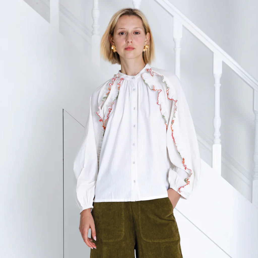 Ecru shirt with stand collar and frill inserts in the armhole and sleeve with a multi-coloured scallop edge.
Bonté Ecru Alice Shirt - Jo And Co Bonté Ecru Alice Shirt - Bonté