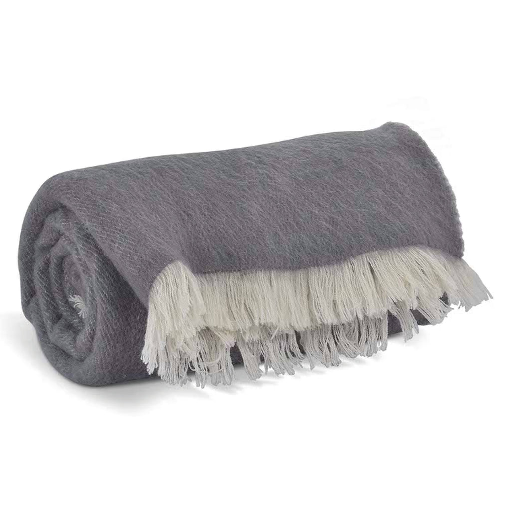 Rolled-up grey throw blanket with white fringe in 100% New Zealand wool.
Grey Wool Leigh Reversible Throw - Jo And Co Grey Wool Leigh Reversible Throw