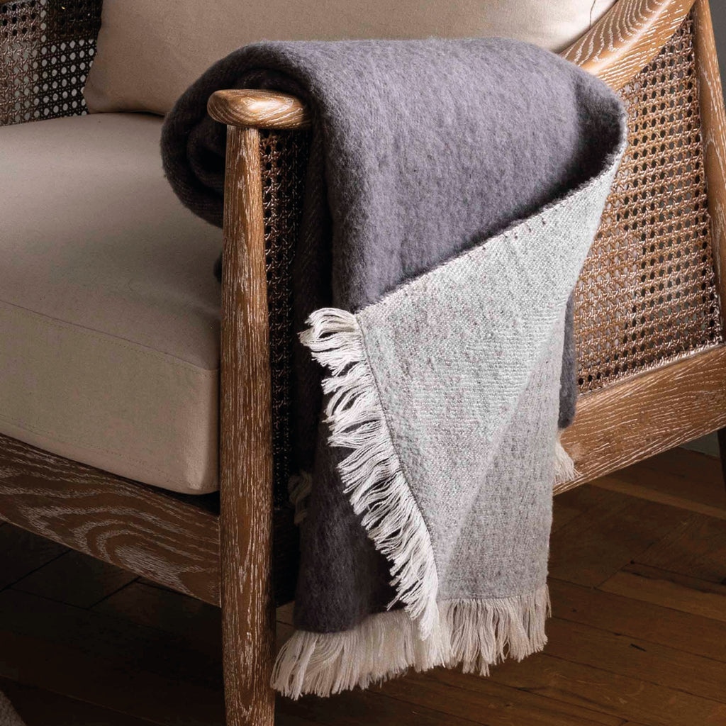 Rolled-up grey throw blanket with white fringe in 100% New Zealand wool.
Grey Wool Leigh Reversible Throw - Jo And Co Grey Wool Leigh Reversible Throw