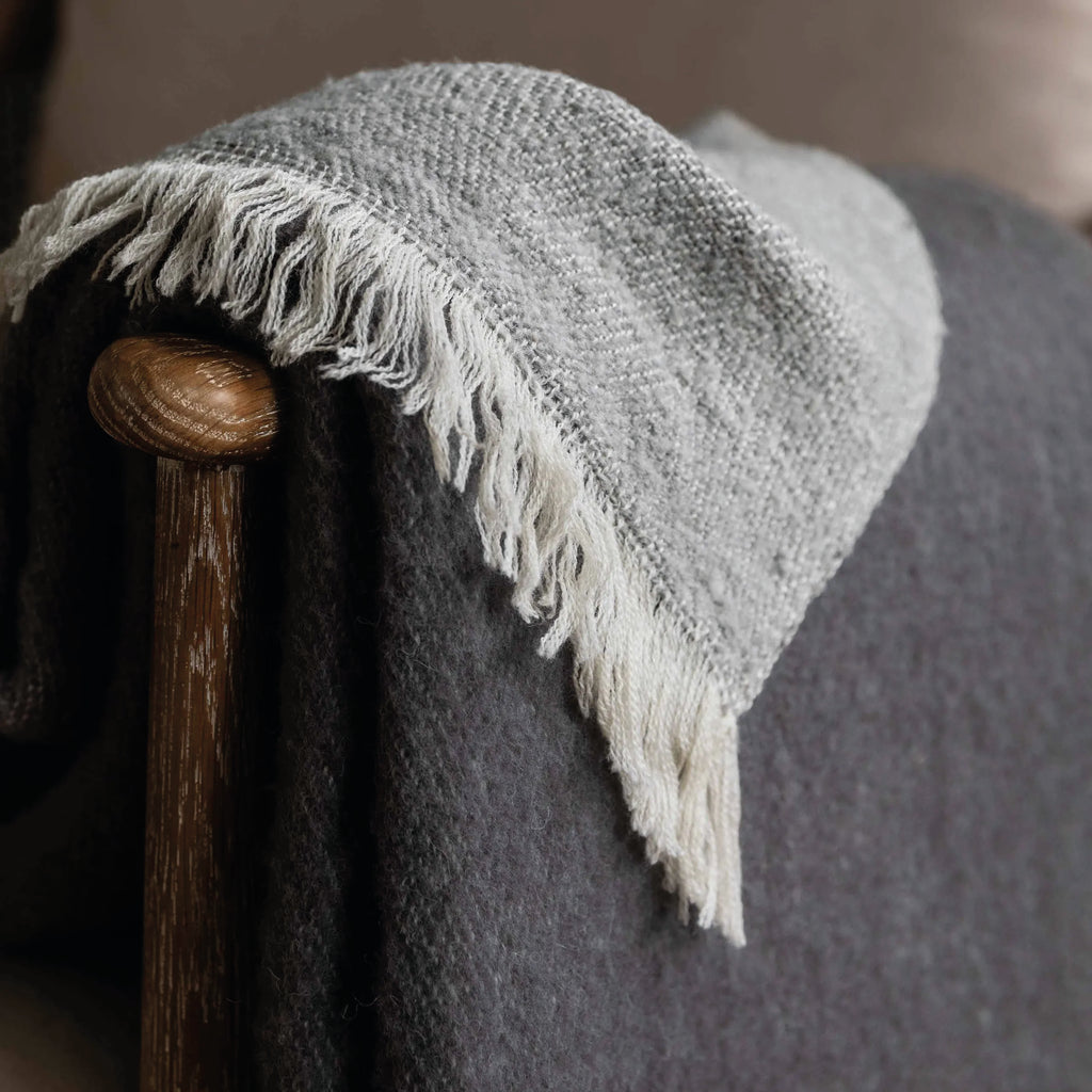 Rolled-up grey throw blanket with white fringe in 100% New Zealand wool.
Grey Wool Leigh Reversible Throw - Jo And Co Grey Wool Leigh Reversible Throw