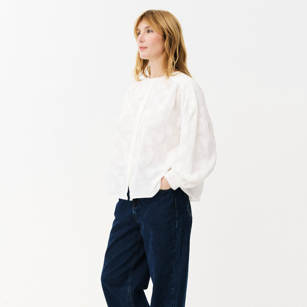 White blouse with cloud-like embroidery, button front, rounded neckline, slightly puffed sleeves with buttoned-cuffs and a gathered yoke at the back. 
Maison Anana White Aniella Blouse - Jo And Co Maison Anana White Aniella Blouse - Maison Anana