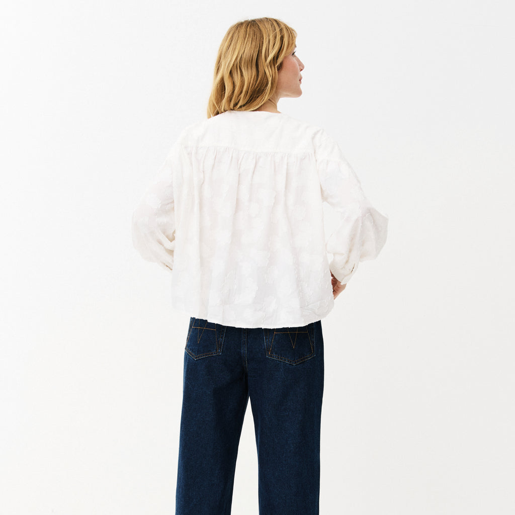 White blouse with cloud-like embroidery, button front, rounded neckline, slightly puffed sleeves with buttoned-cuffs and a gathered yoke at the back. 
Maison Anana White Aniella Blouse - Jo And Co Maison Anana White Aniella Blouse - Maison Anana