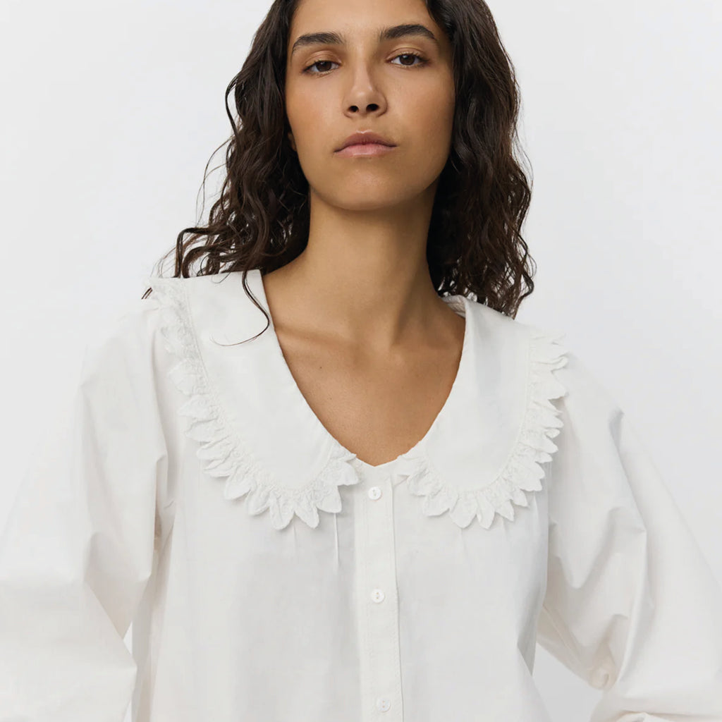 White shirt with short boxy fit, puff sleeves and Peter Pan collar with embroidered frill edge.
Sofie Schnoor Cream Manon Shirt - Jo And Co Sofie Schnoor Cream Manon Shirt - Sofie Schnoor
