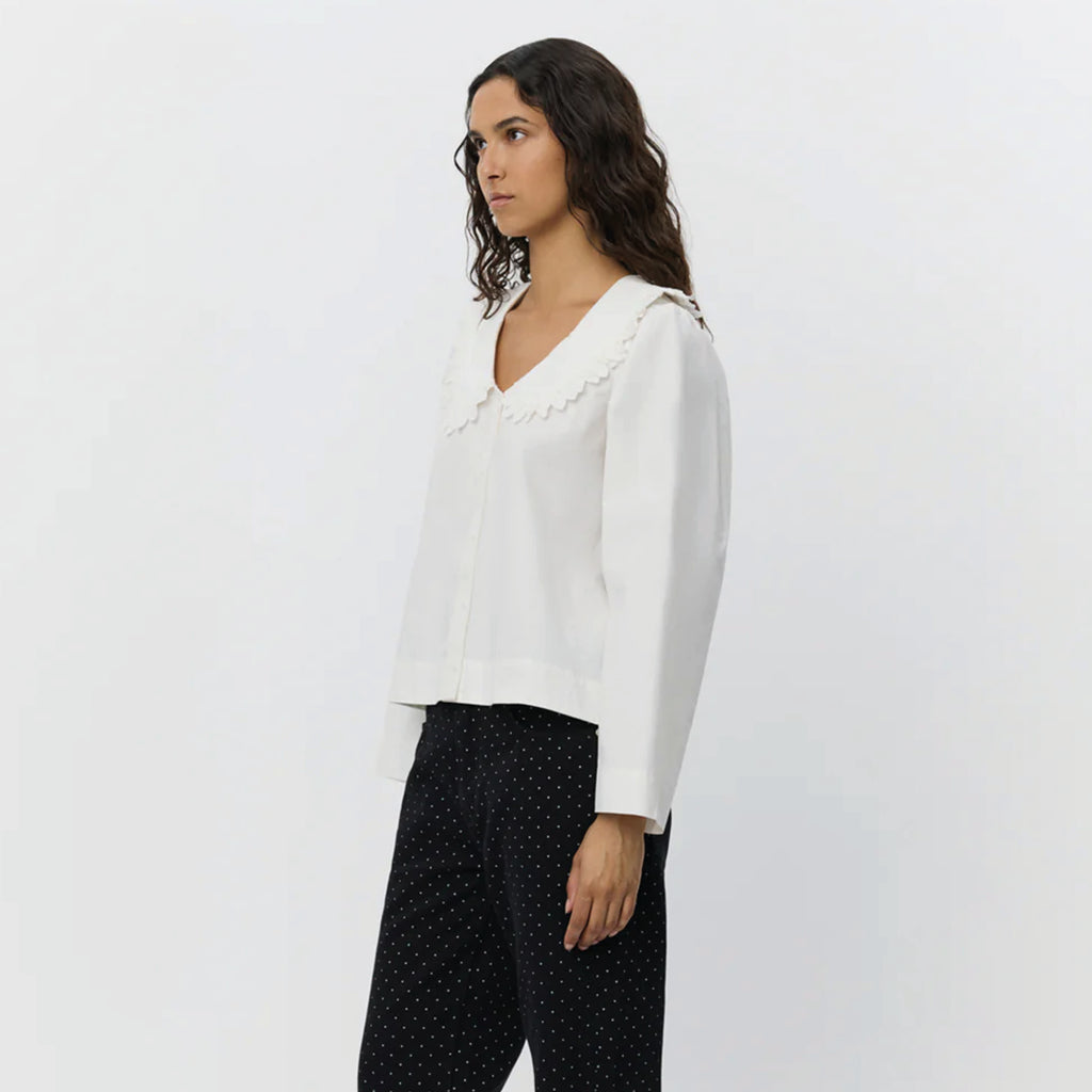 White shirt with short boxy fit, puff sleeves and Peter Pan collar with embroidered frill edge.
Sofie Schnoor Cream Manon Shirt - Jo And Co Sofie Schnoor Cream Manon Shirt - Sofie Schnoor