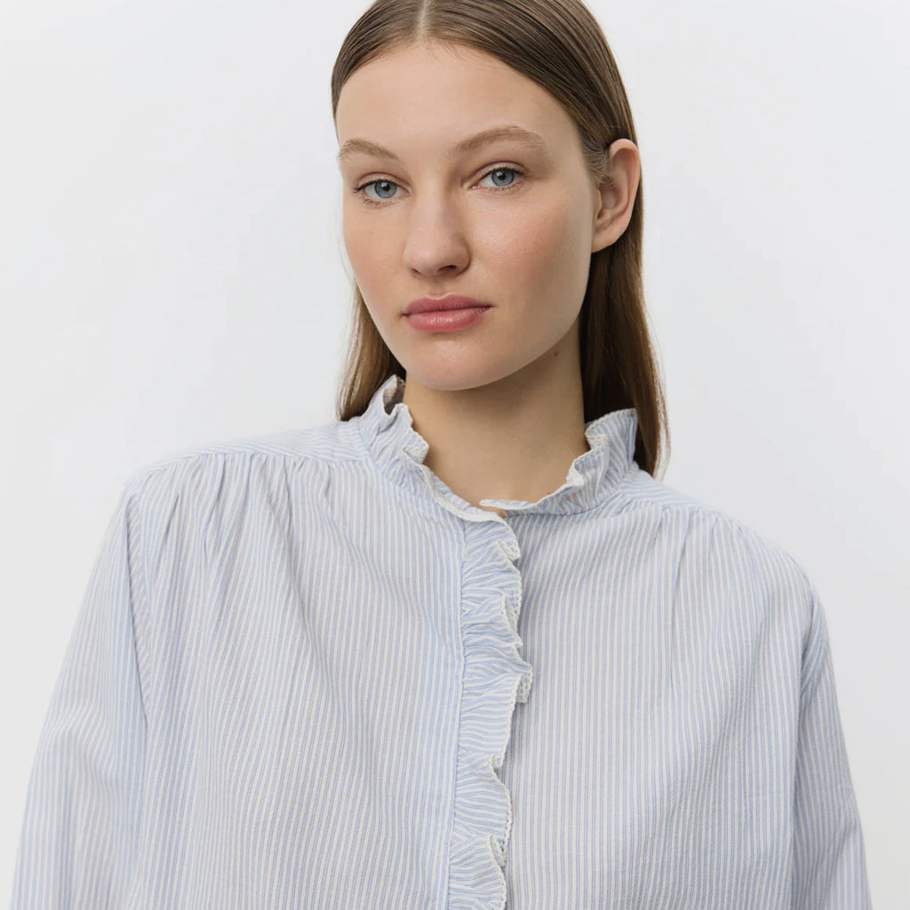 Light blue striped shirt with frilled collar with decorative edge along button placket and wrinkle details on shoulders.
Sofie Schnoor Light Blue Striped Edna Shirt - Jo And Co Sofie Schnoor Light Blue Striped Edna Shirt - Sofie Schnoor