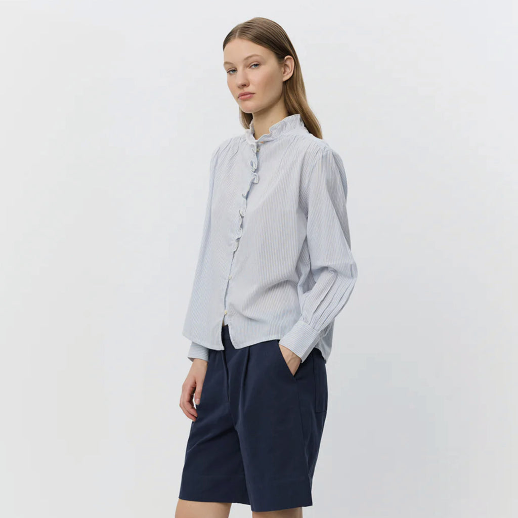 Light blue striped shirt with frilled collar with decorative edge along button placket and wrinkle details on shoulders.
Sofie Schnoor Light Blue Striped Edna Shirt - Jo And Co Sofie Schnoor Light Blue Striped Edna Shirt - Sofie Schnoor