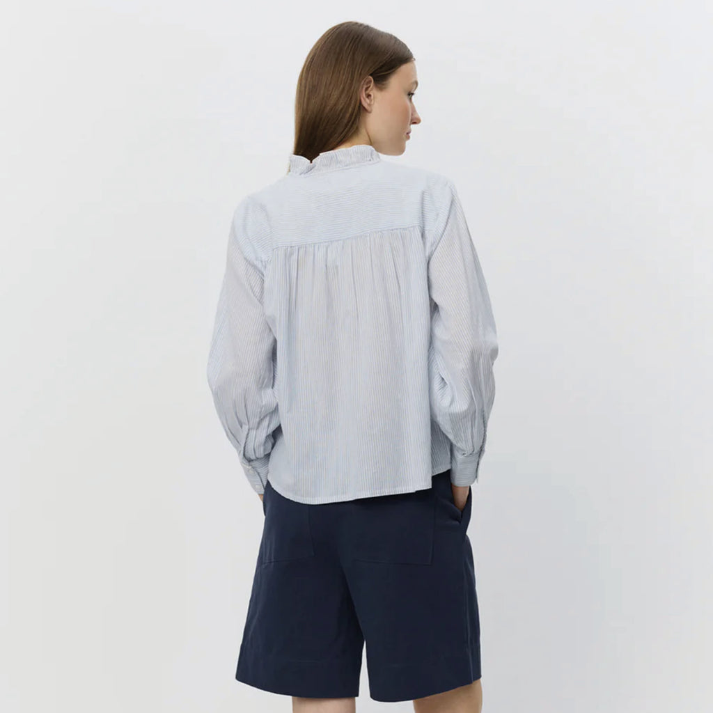 Light blue striped shirt with frilled collar with decorative edge along button placket and wrinkle details on shoulders.
Sofie Schnoor Light Blue Striped Edna Shirt - Jo And Co Sofie Schnoor Light Blue Striped Edna Shirt - Sofie Schnoor